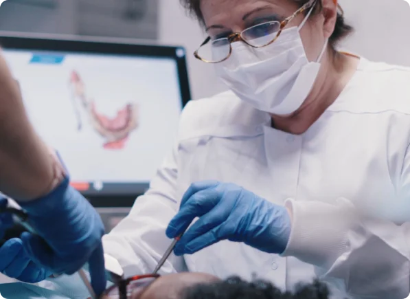 Dentist consulting patient about cavity treatment with digital image on screen behind 